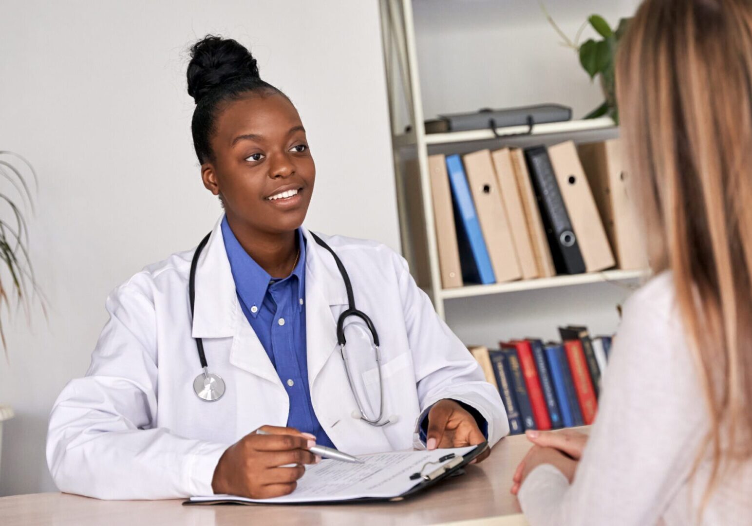 African doctor physician consulting caucasian woman patient at medical visit.